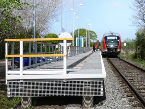 Der Zug stoppt am Bahnsteig aus GFK mit Geländer